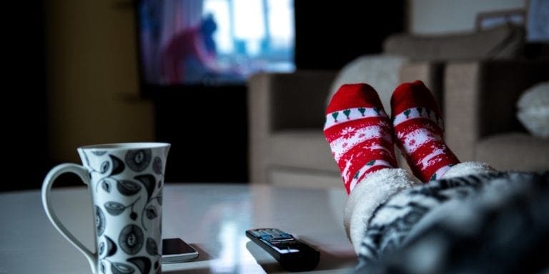 woman with warm socks on and a mug watching tv with heat on