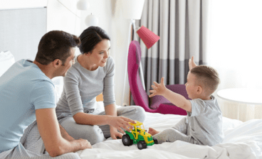 happy family playing on bed with tractor